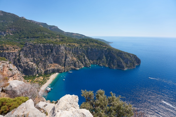 Kelebekler Vadisi, Muğla'da yüksek kayalıklardan görünen mavi koy ve yemyeşil doğa manzarası.