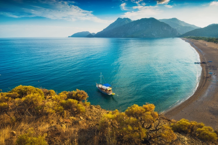 Olimpos, Antalya'da mavi sulara sahip koy ve dağlarla çevrili sahil manzarası.