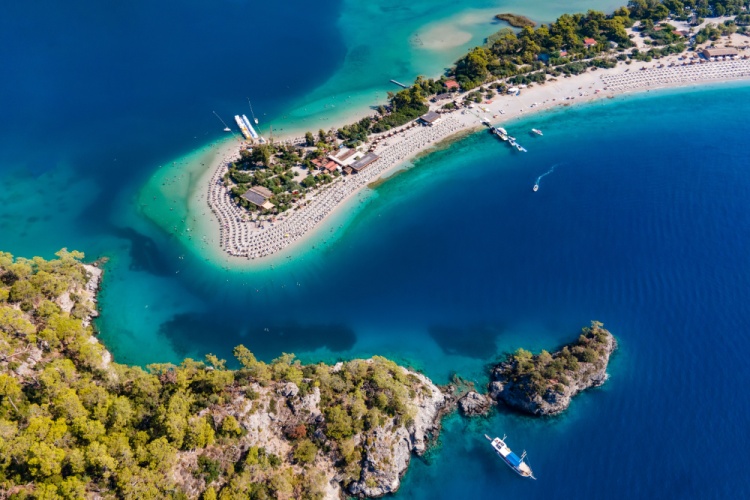 Ölüdeniz, Muğla'da turkuaz renkli deniz ve kumsalla çevrili sahil manzarası.